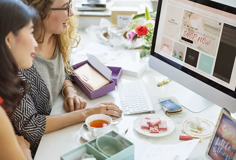 Dos mujeres navegando por una tienda online atractiva en una computadora