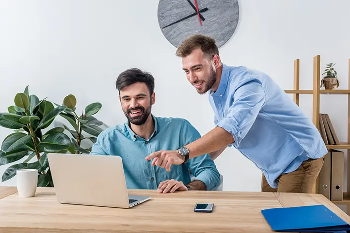 Web developer explaining a solution to her client in front of a laptop, representing the value of human guidance alongside artificial intelligence.