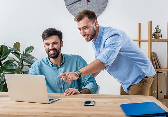 Desarrollador web explicando una solución a su clienta frente a una laptop, representando el valor de la asesoría humana frente a la inteligencia artificial.