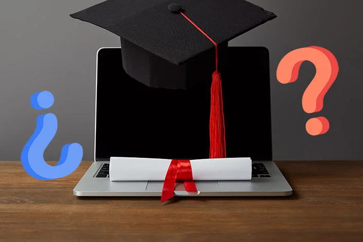 Laptop con birrete de graduación, diploma y signos de interrogación representando duda sobre título universitario